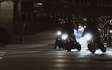 A group of banner bikers riding in formation, their lights creating a vibrant trail.