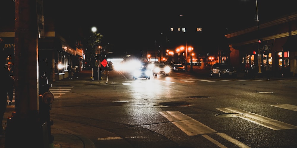 a city street at night with cars driving on it