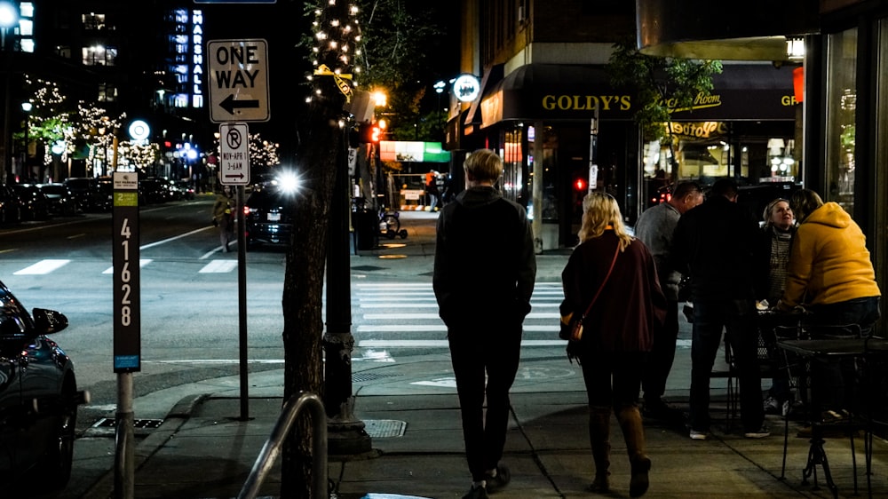 a group of people walking down a street at night