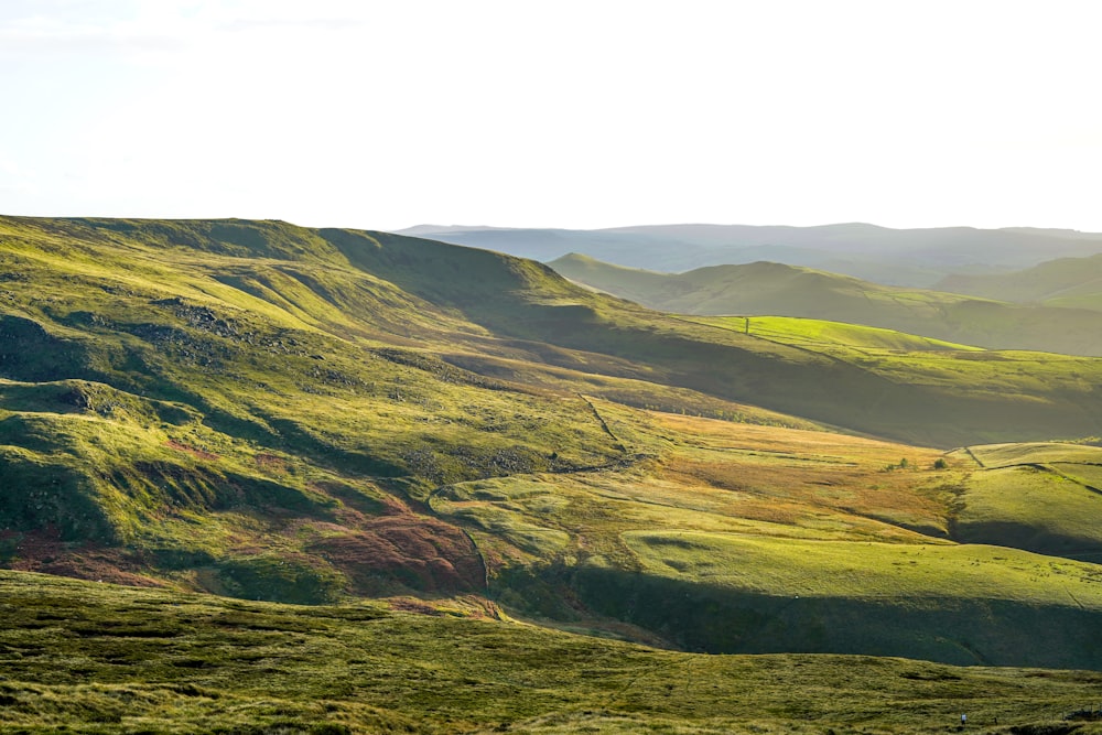 a view of a grassy hill with hills in the background