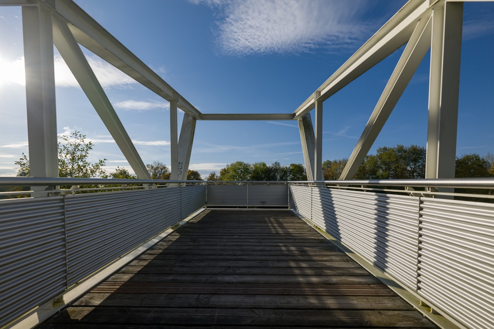 a wooden walkway with a white fence and blue sky in the background