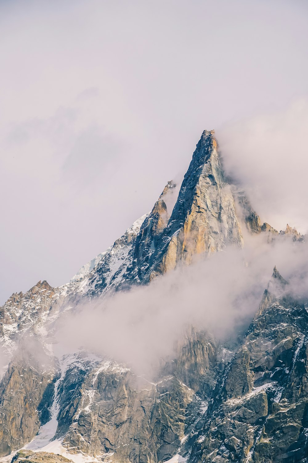 a very tall mountain covered in snow and clouds