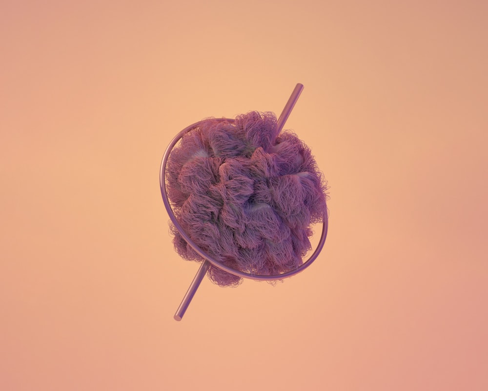 a purple ball of yarn sitting on top of a metal pole