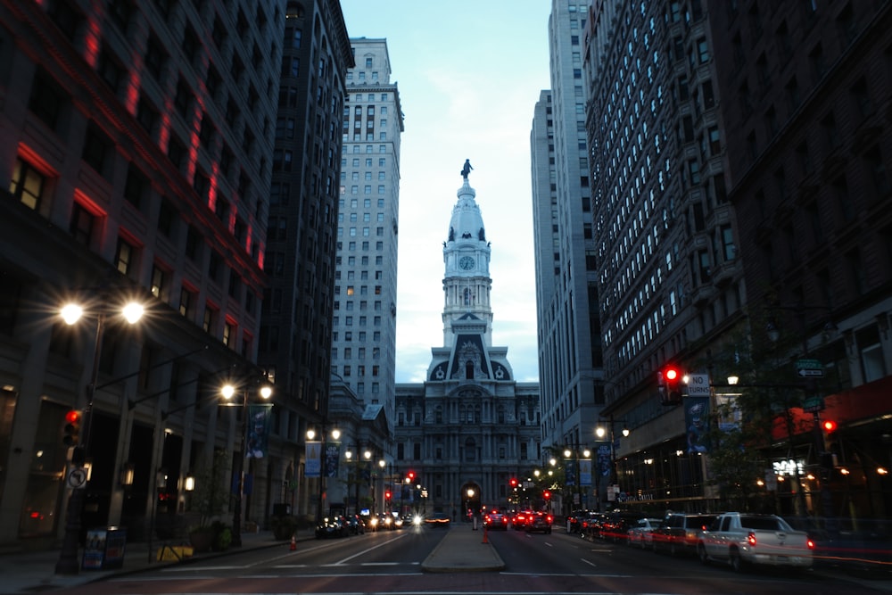 a city street with tall buildings and a clock tower