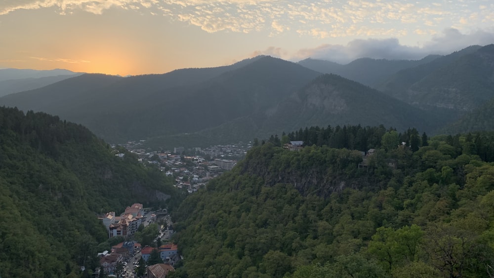 the sun is setting over a small town in the mountains