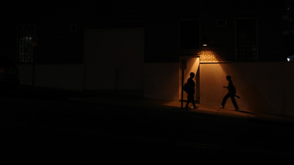 a couple of people walking down a street at night