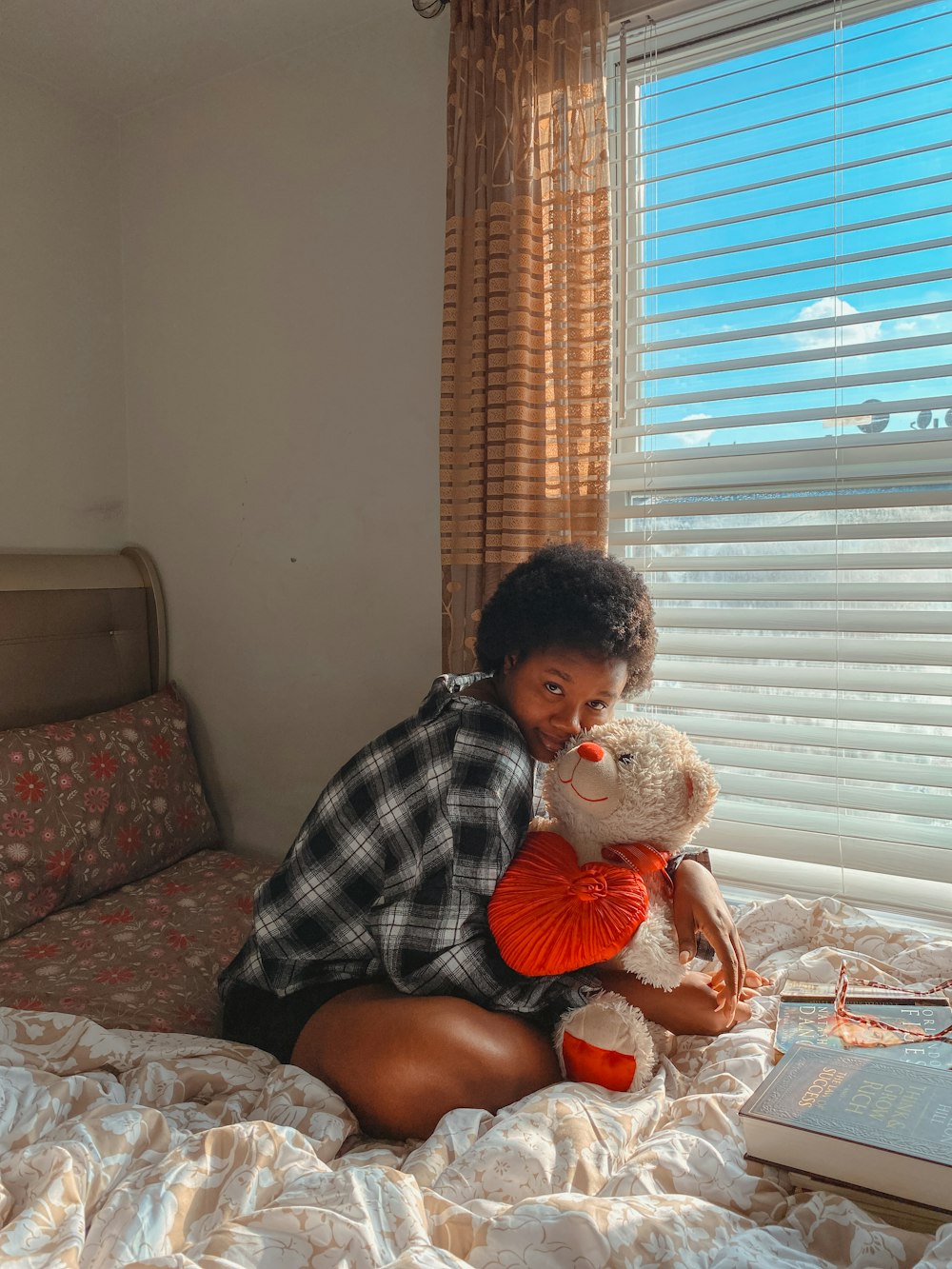 a woman sitting on a bed holding a teddy bear