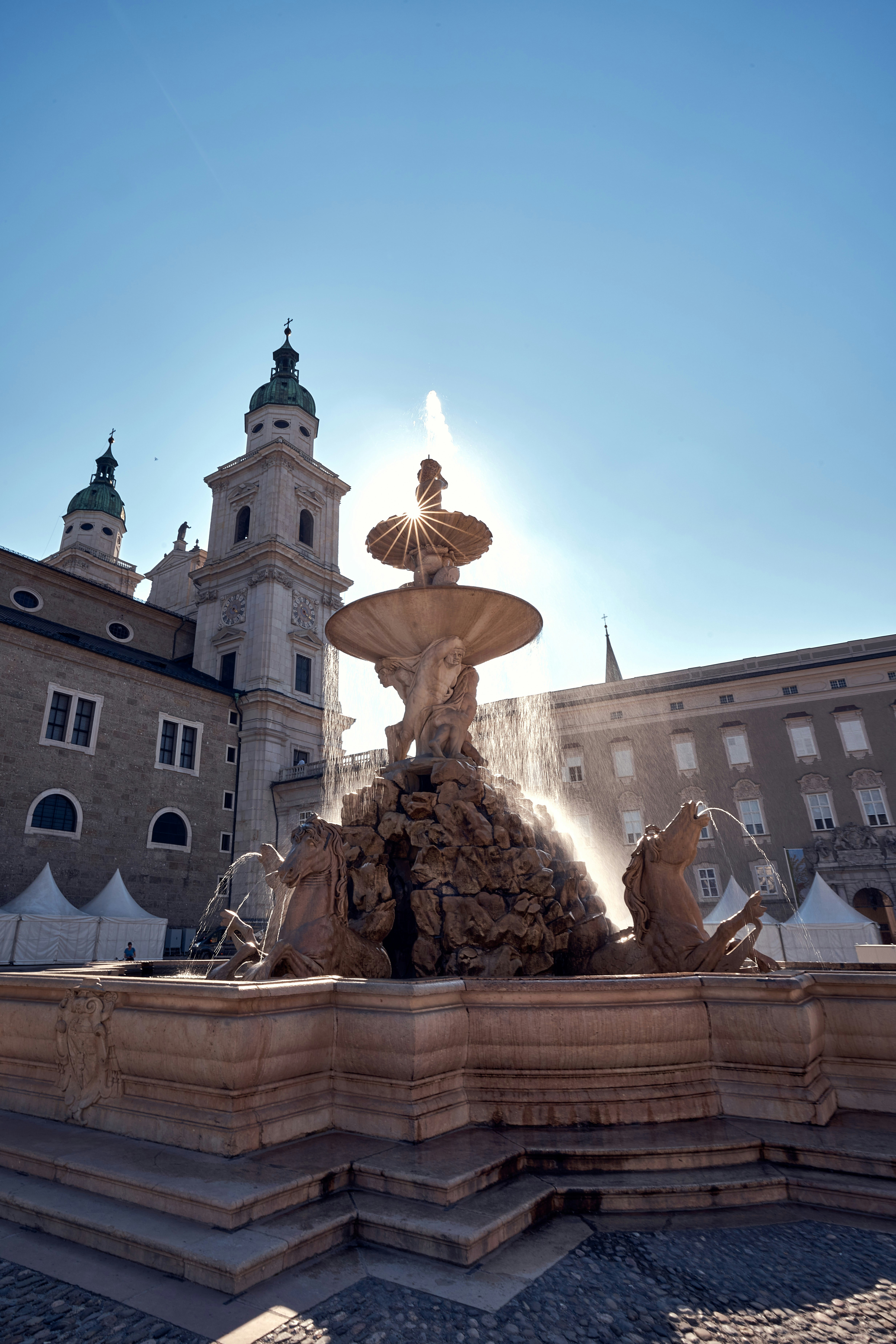 a fountain in front of a building with a clock tower in the background