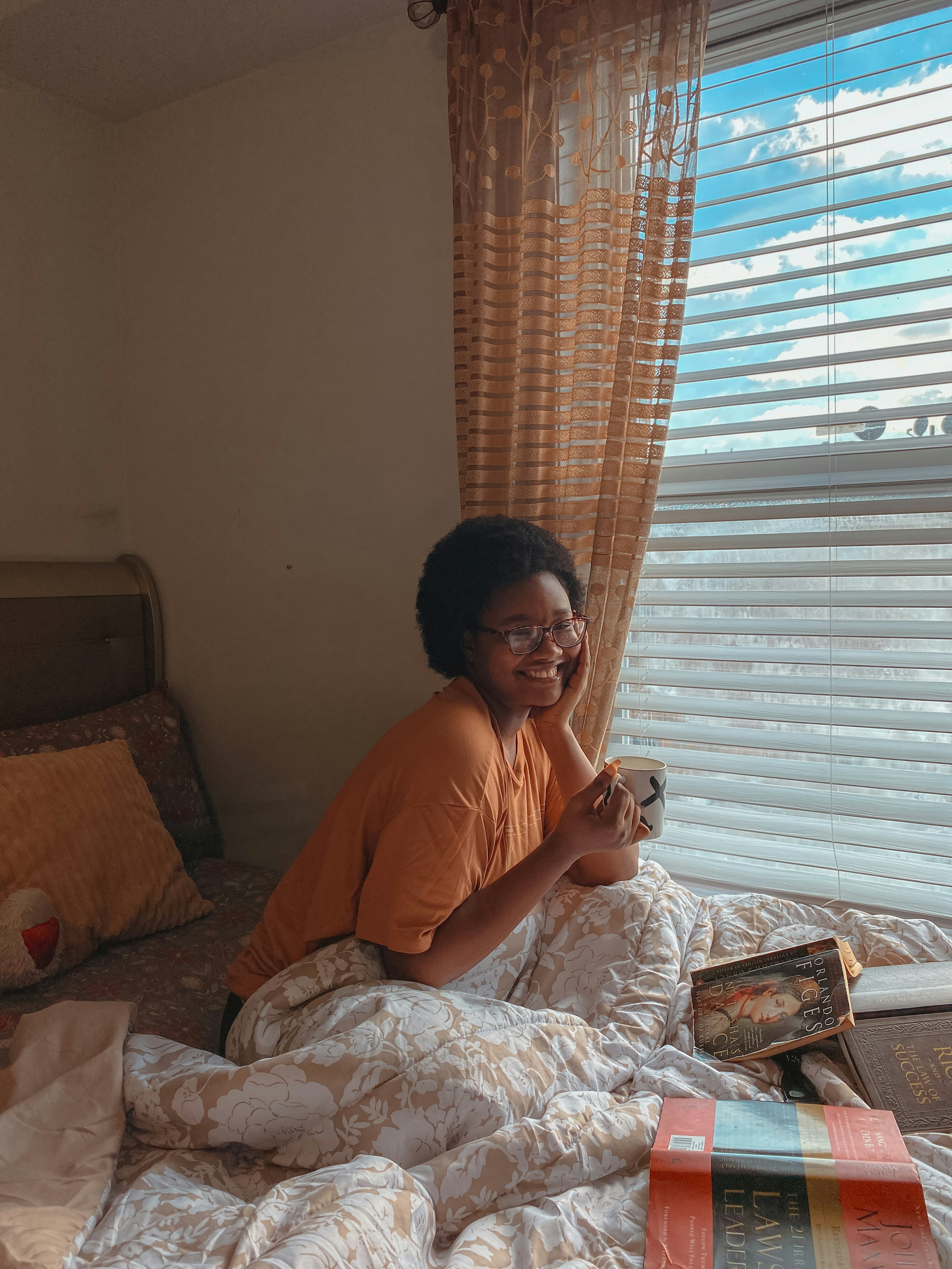 a woman sitting on a bed talking on a cell phone