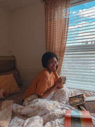 a woman sitting on a bed talking on a cell phone