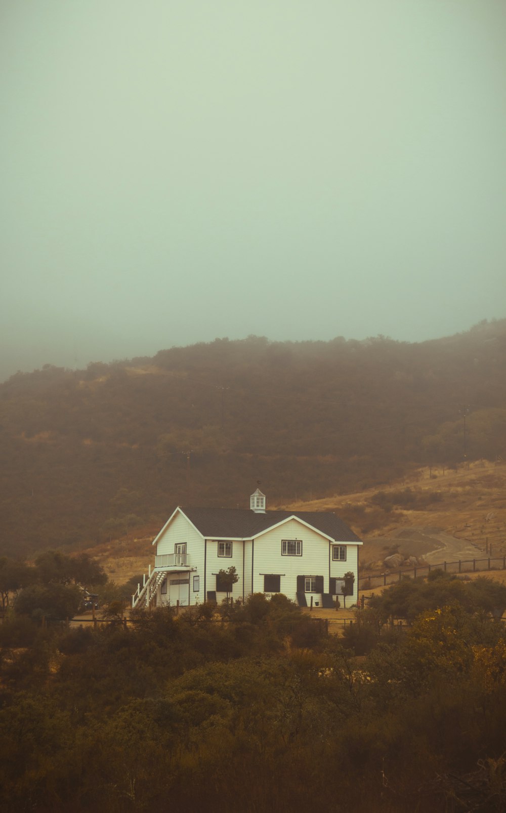 Une grande maison blanche assise au sommet d’une colline verdoyante