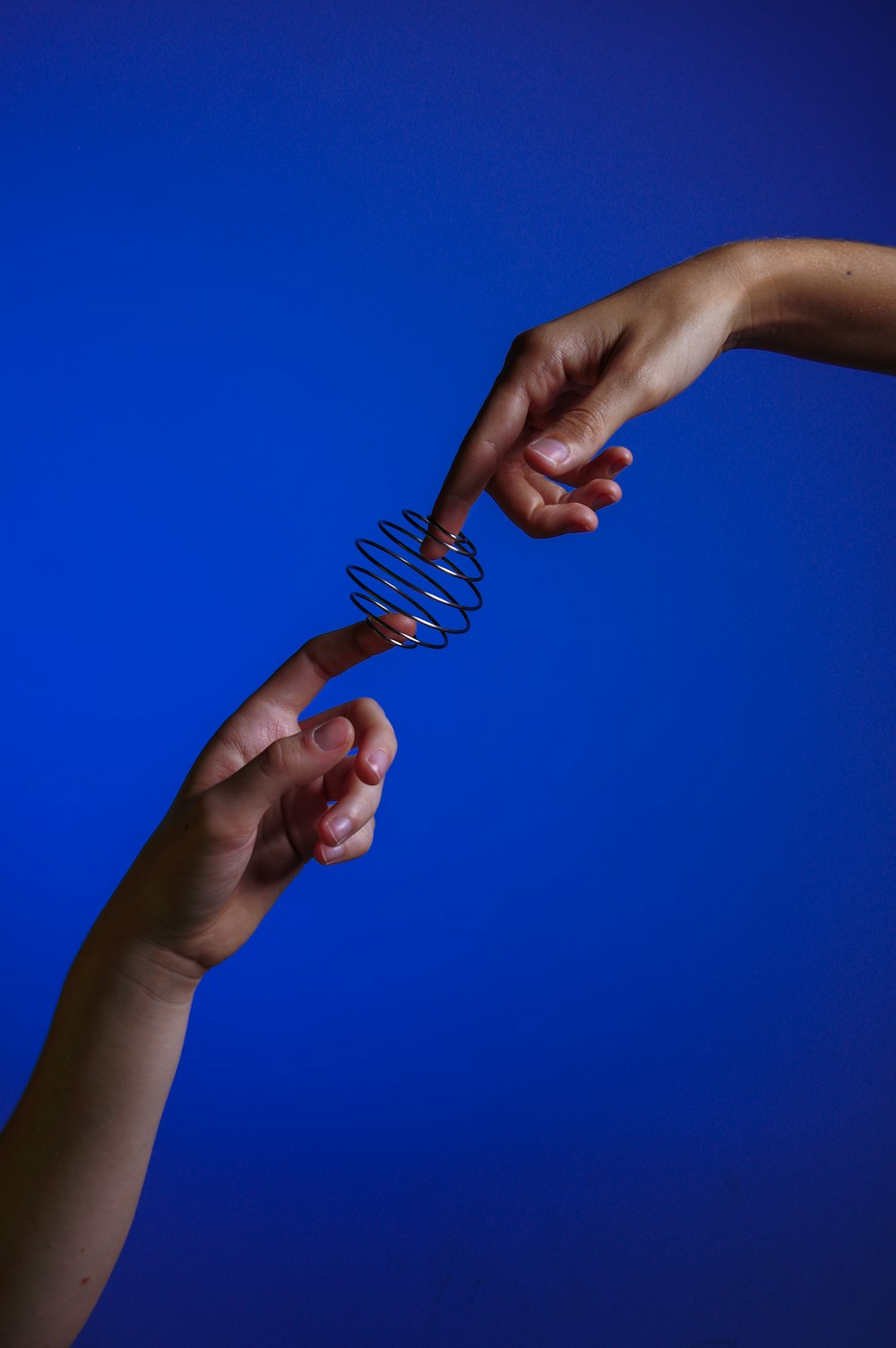 two hands reaching for a spiral object against a blue background
