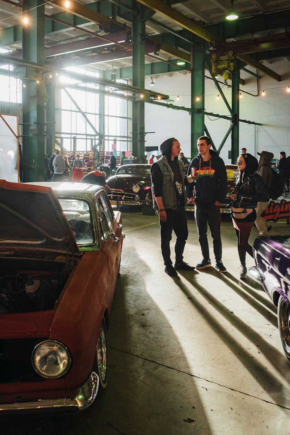 a couple of men standing next to a car in a garage