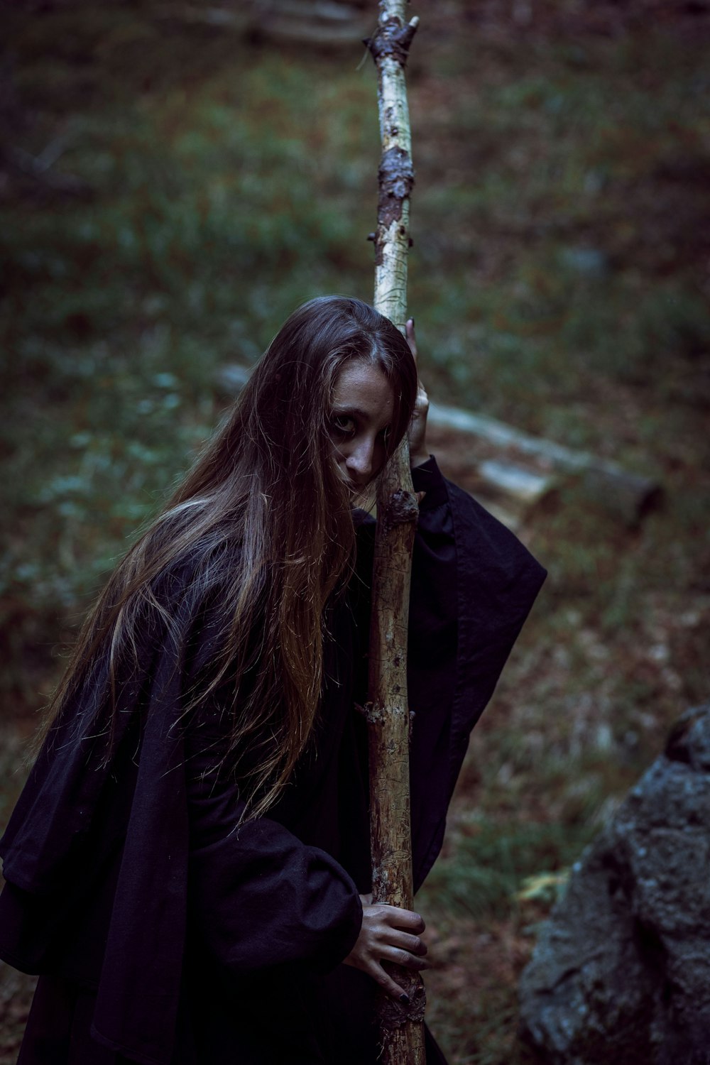 a woman with long hair holding a stick