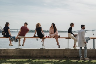 a group of people sitting on a bench next to a body of water
