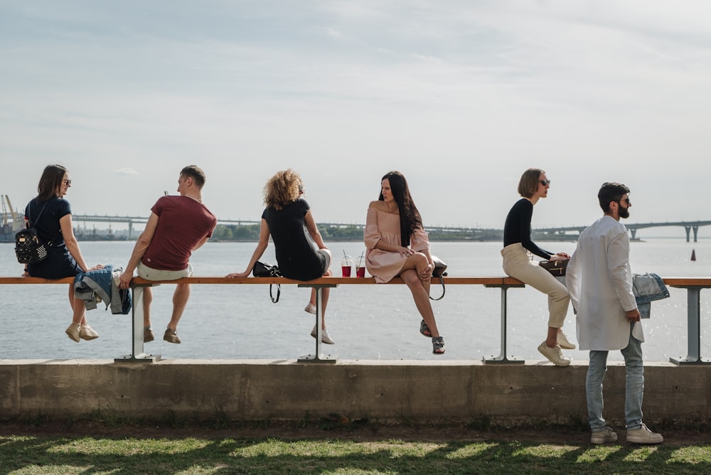 a group of people sitting on a bench next to a body of water