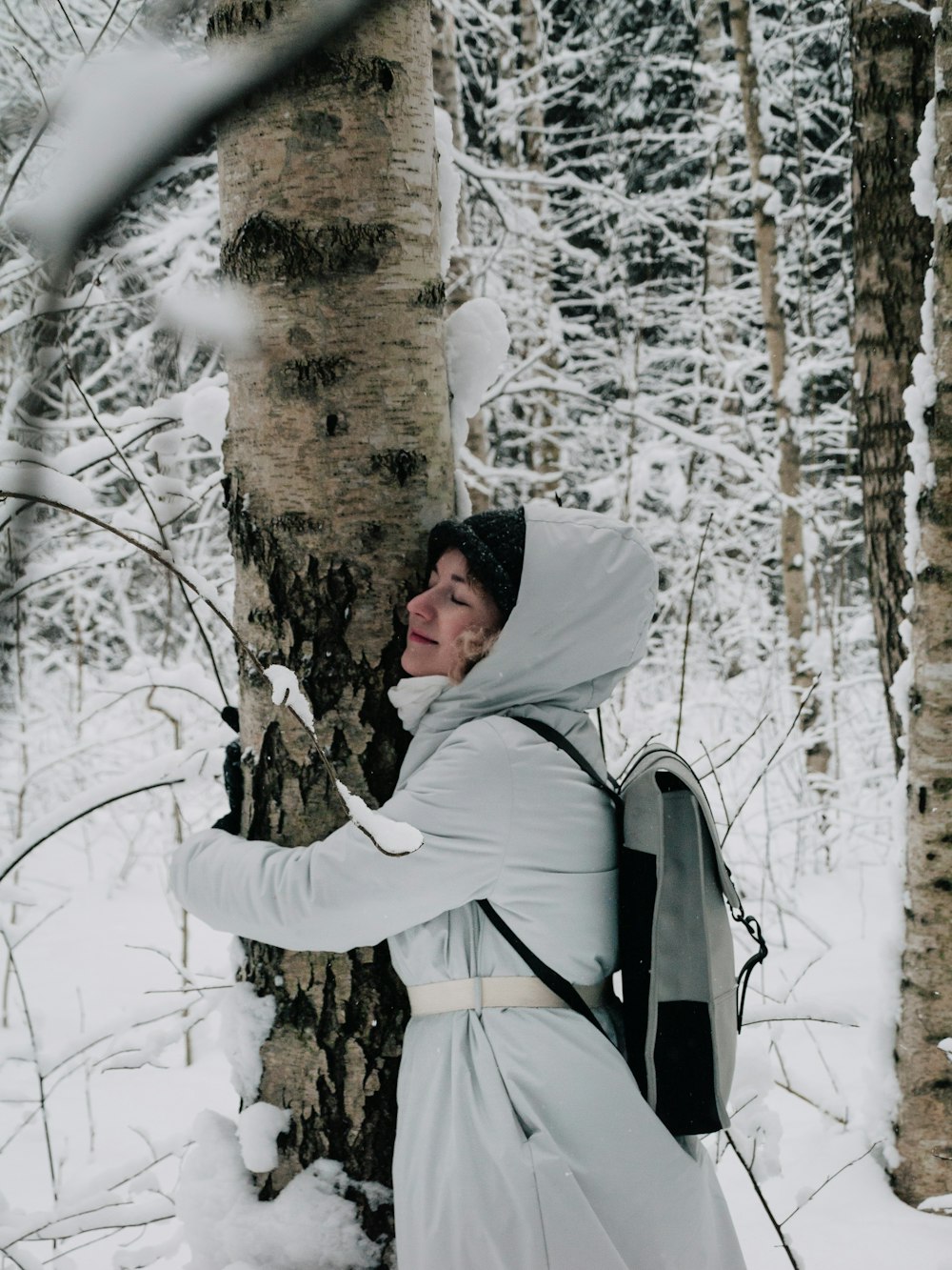 a woman in a white dress standing next to a tree