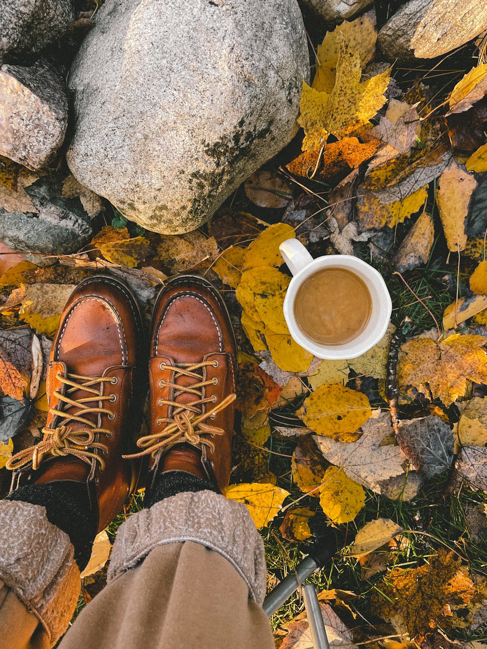 los pies de una persona y una taza de café en el suelo