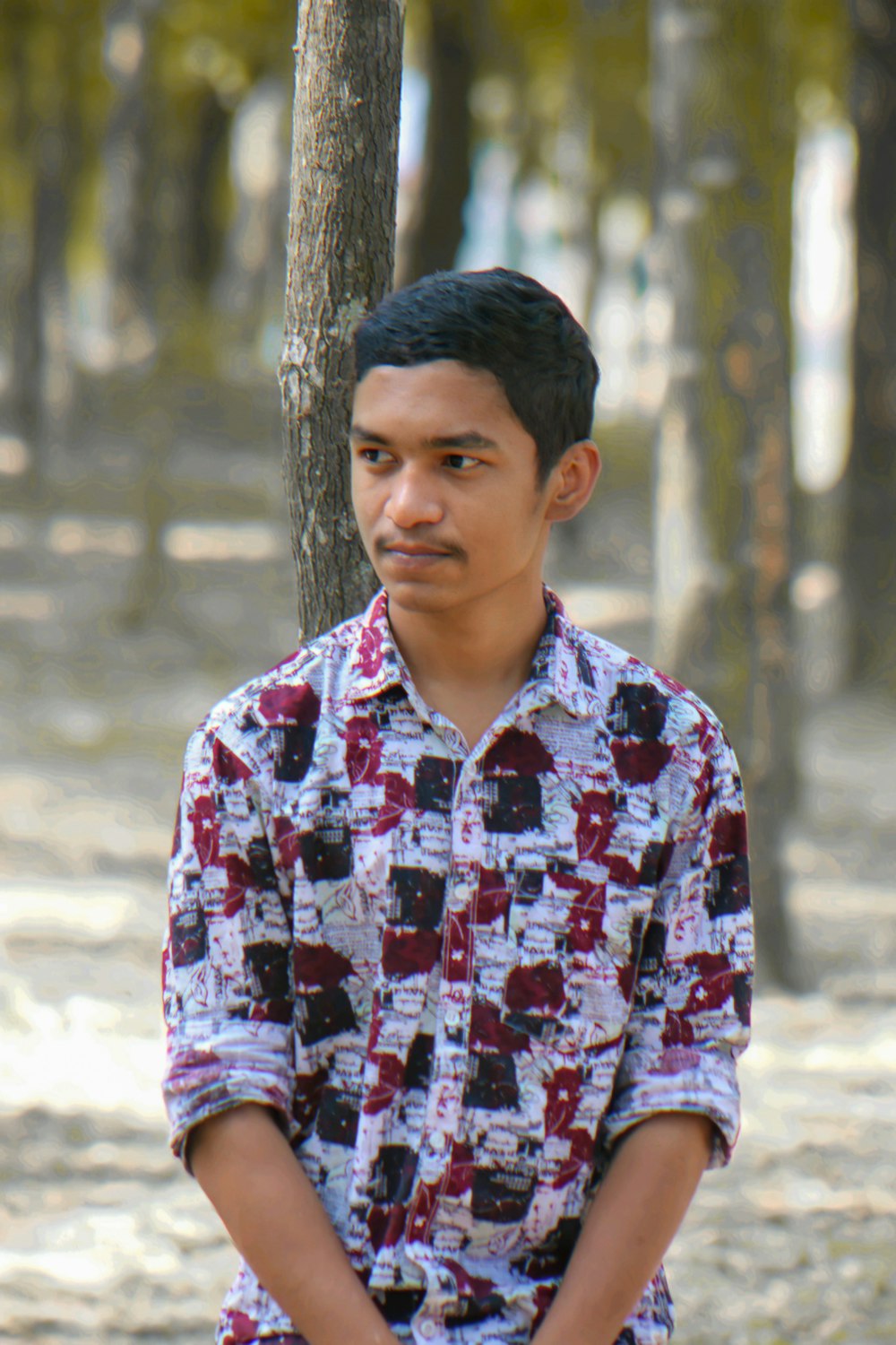 a man standing next to a tree in a forest