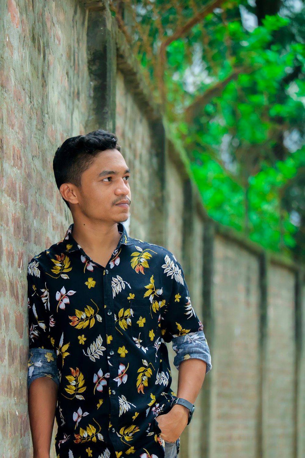 a man standing next to a brick wall