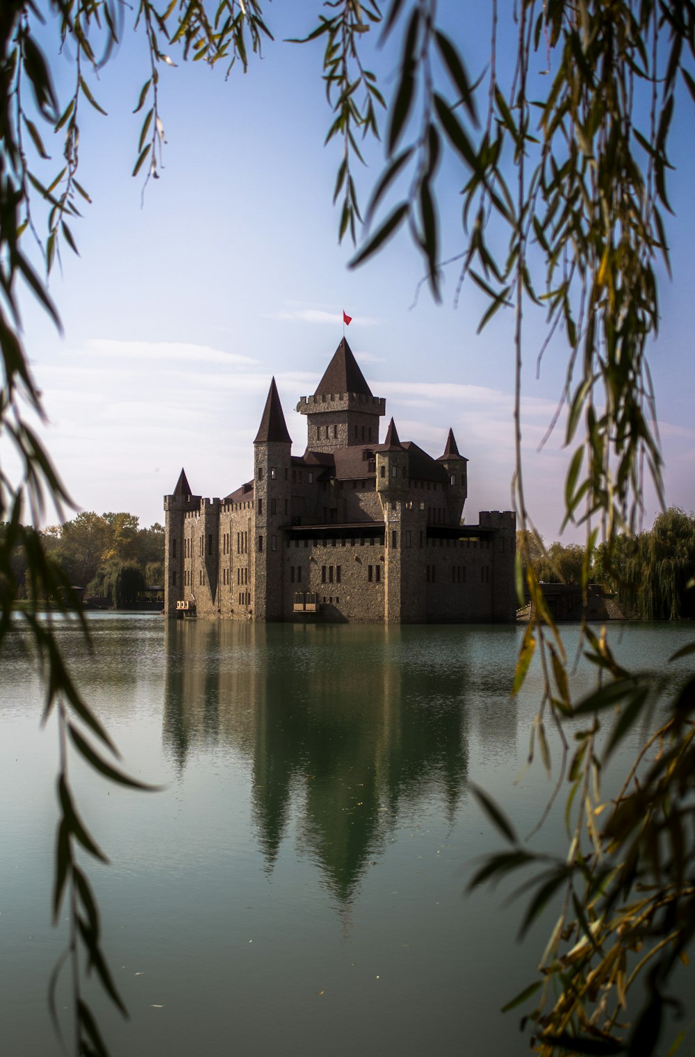 a castle sitting on top of a lake surrounded by trees