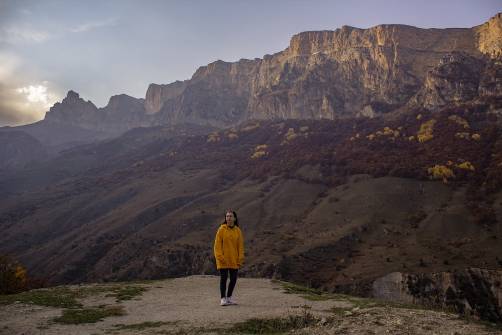 Una donna in una giacca gialla in piedi su una collina