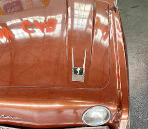 A sleek vintage car hood gleaming under soft garage lighting with gold accents.