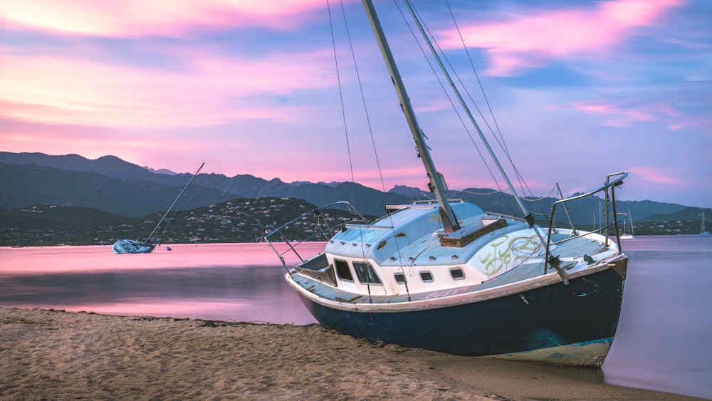 a boat sitting on top of a beach next to a body of water