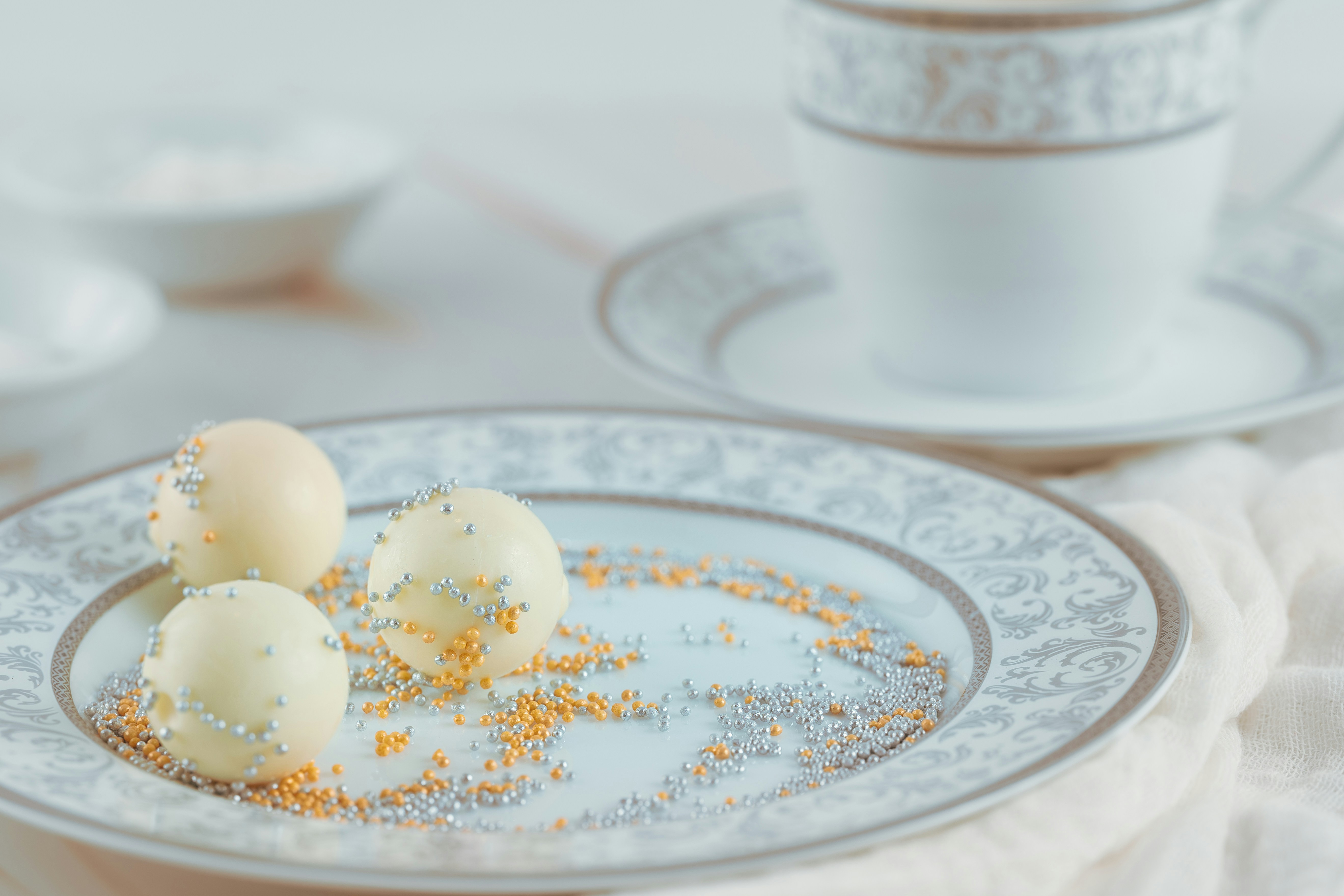 Image shows white chocolate balls on a plate served with tea.