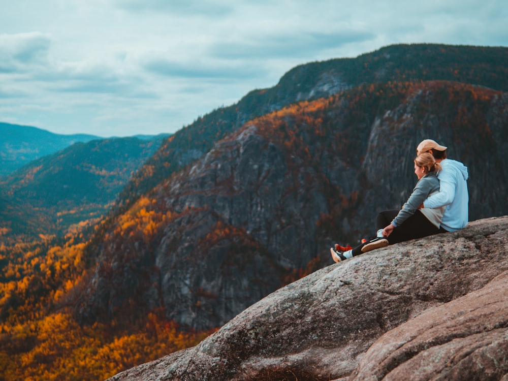 a woman sitting on top of a large rock