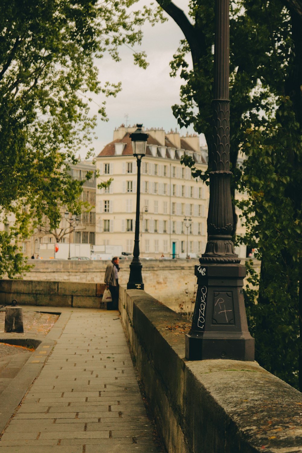 a couple of people sitting on a bench under a lamp post