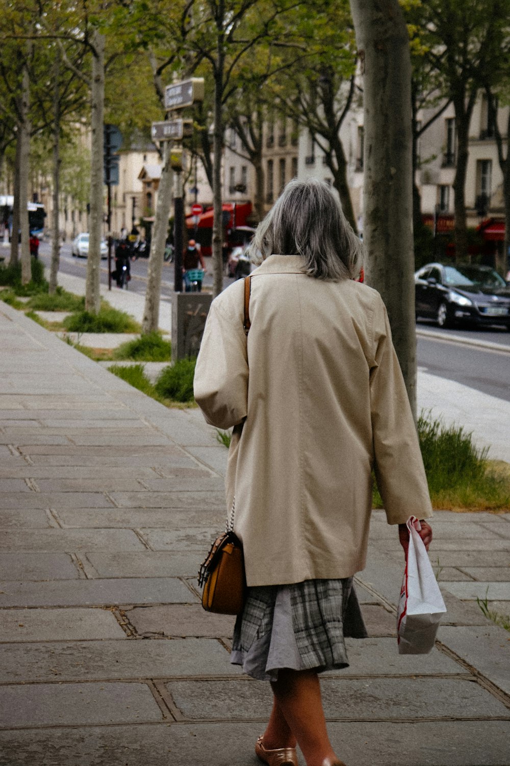 a woman walking down a sidewalk carrying shopping bags