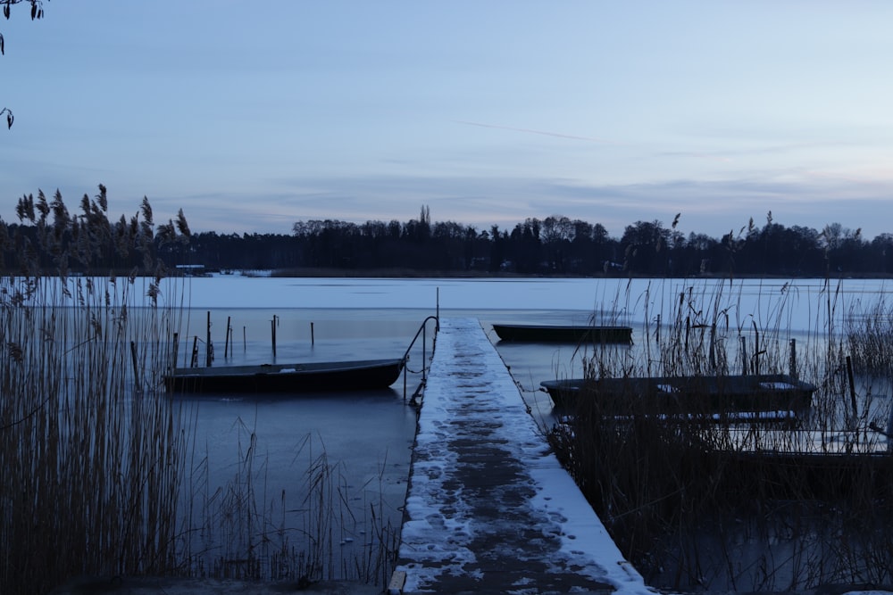 two boats are docked on a frozen lake