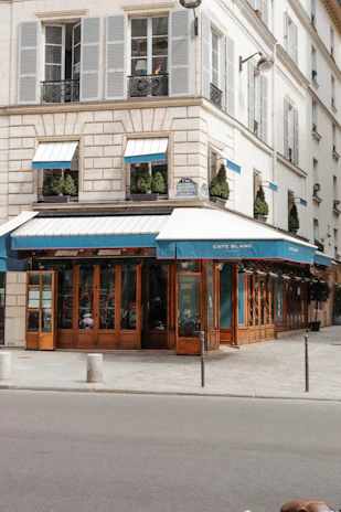 Custom-made exterior awning in deep blue over a café facade in Nice.