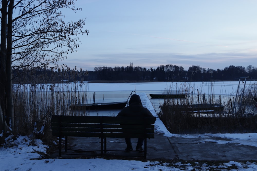 a person sitting on a bench near a body of water