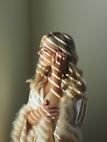 A serene moment of a woman wrapped in a silk robe, sitting by a window with soft natural light.
