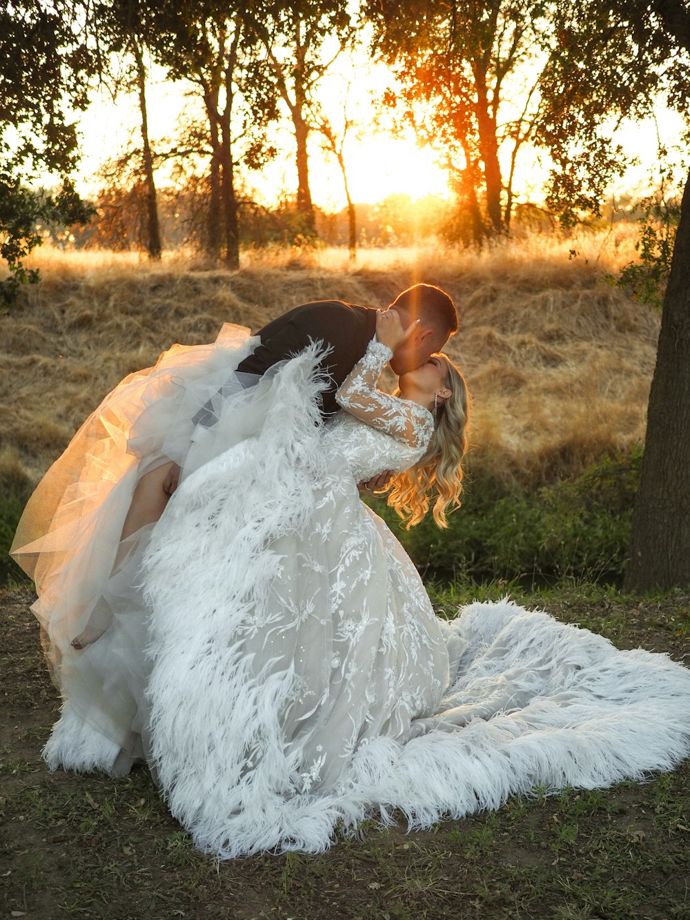 a bride and groom kissing under a tree