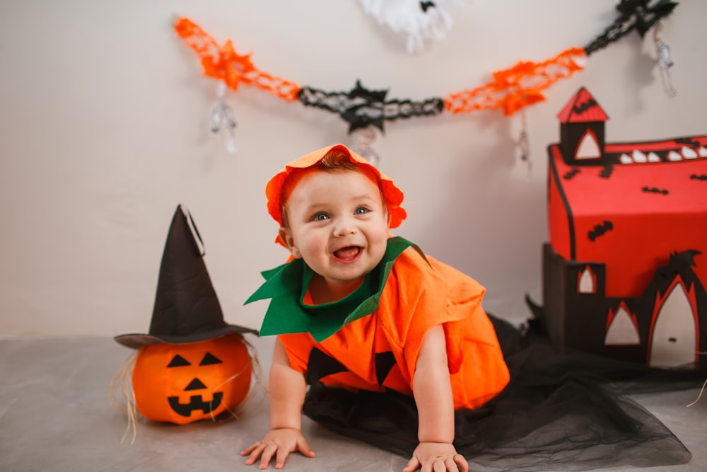 a baby in a halloween costume laying on the floor