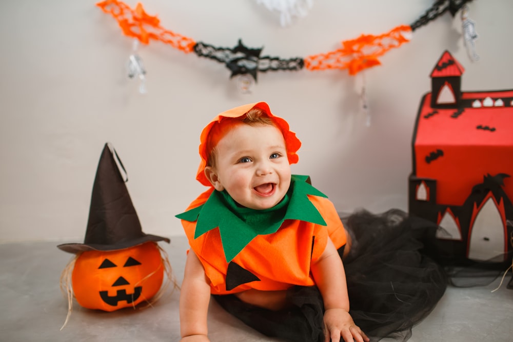 a baby in a halloween costume sitting on the floor