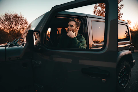 a man sitting in the driver seat of a car with door open waiting