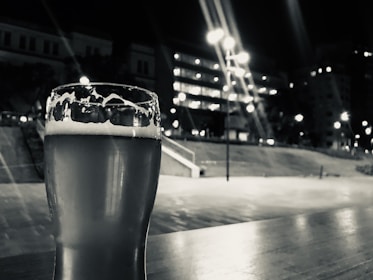 a glass of beer sitting on top of a wooden table