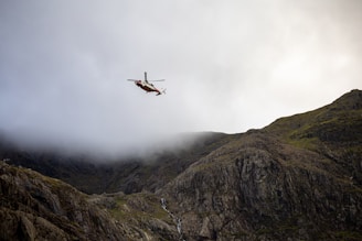 A Robinson R66 helicopter flying over a scenic landscape.
