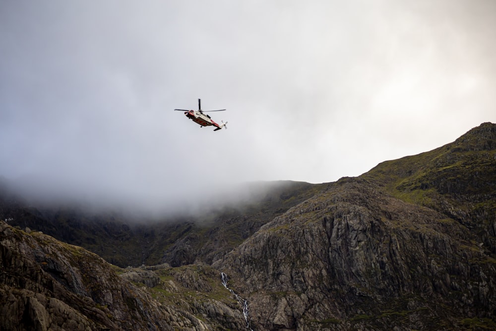 a helicopter flying over a mountain with a waterfall