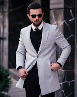 a man in a suit and sunglasses standing on a sidewalk