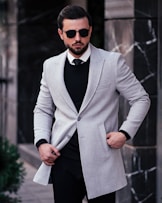 a man in a suit and sunglasses standing on a sidewalk