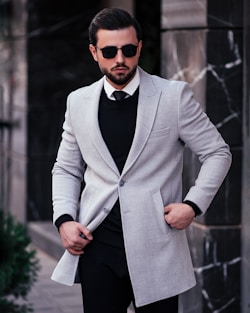 a man in a suit and sunglasses standing on a sidewalk
