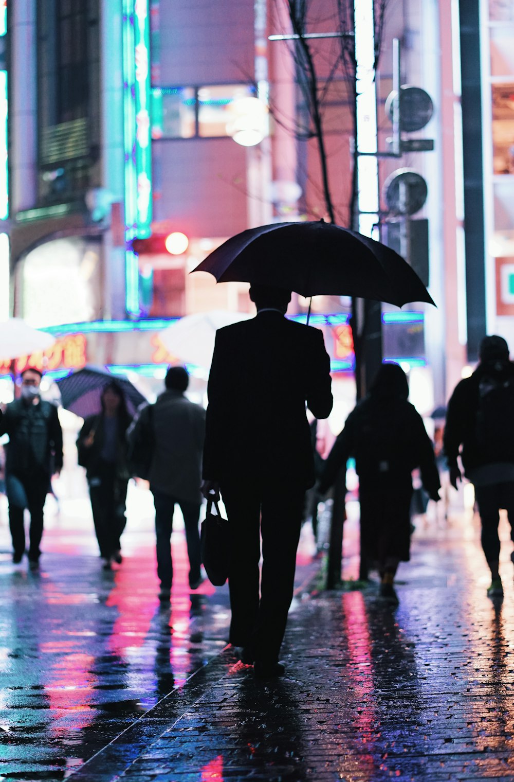 Ein Mann geht eine Straße entlang und hält einen Regenschirm in der Hand