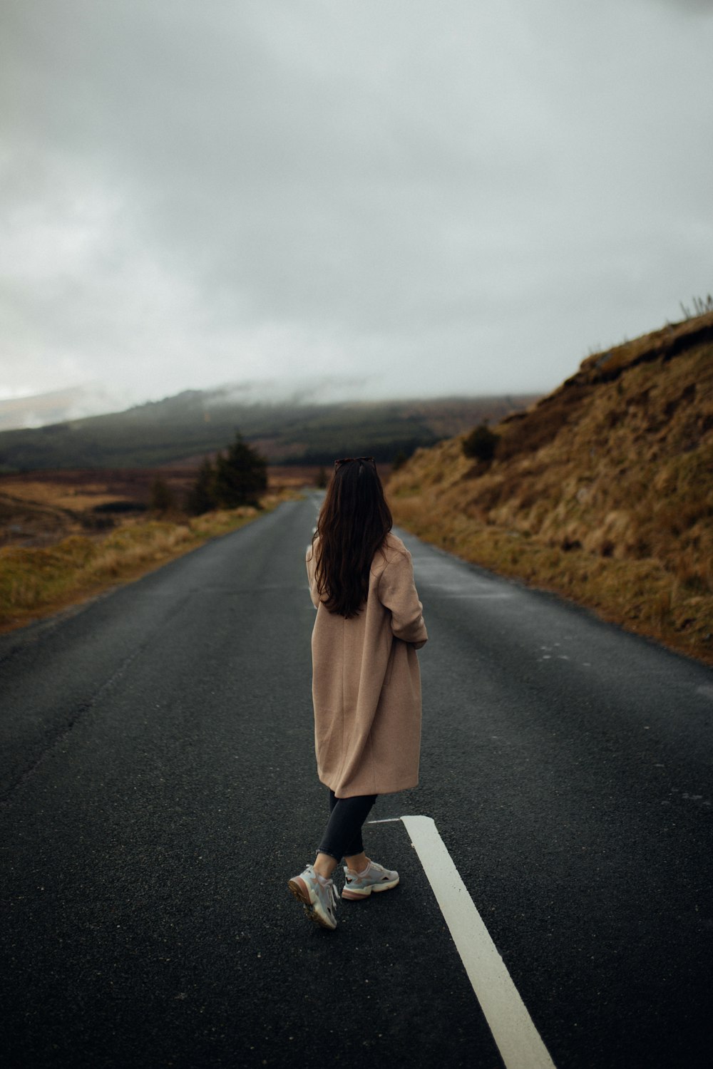a woman walking down the middle of a road