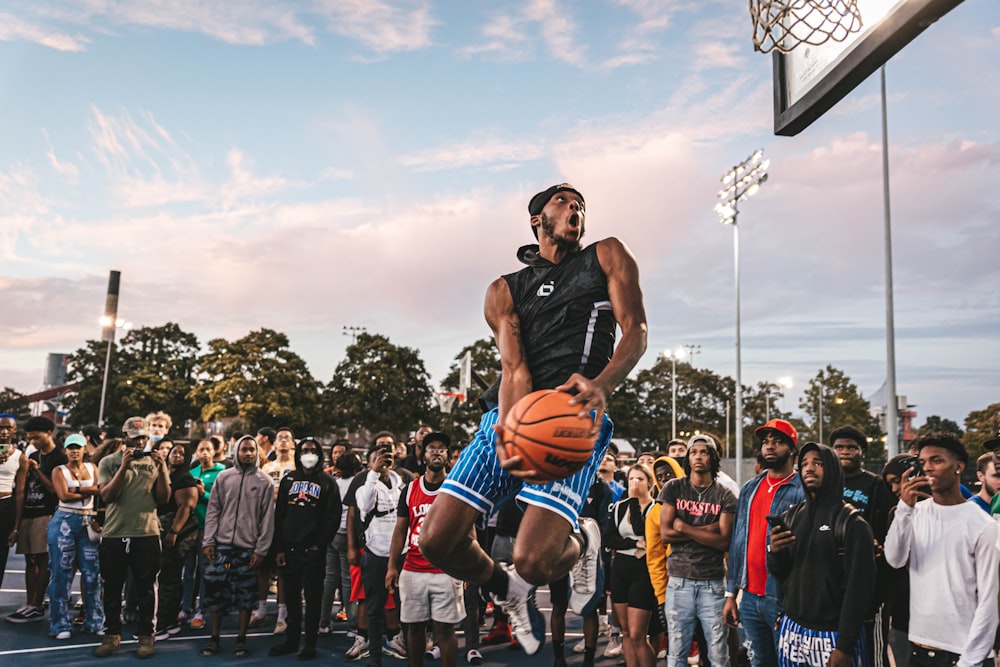 a group of people watching a man dunking a basketball