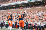Football athlete celebrating a touchdown with fans roaring.